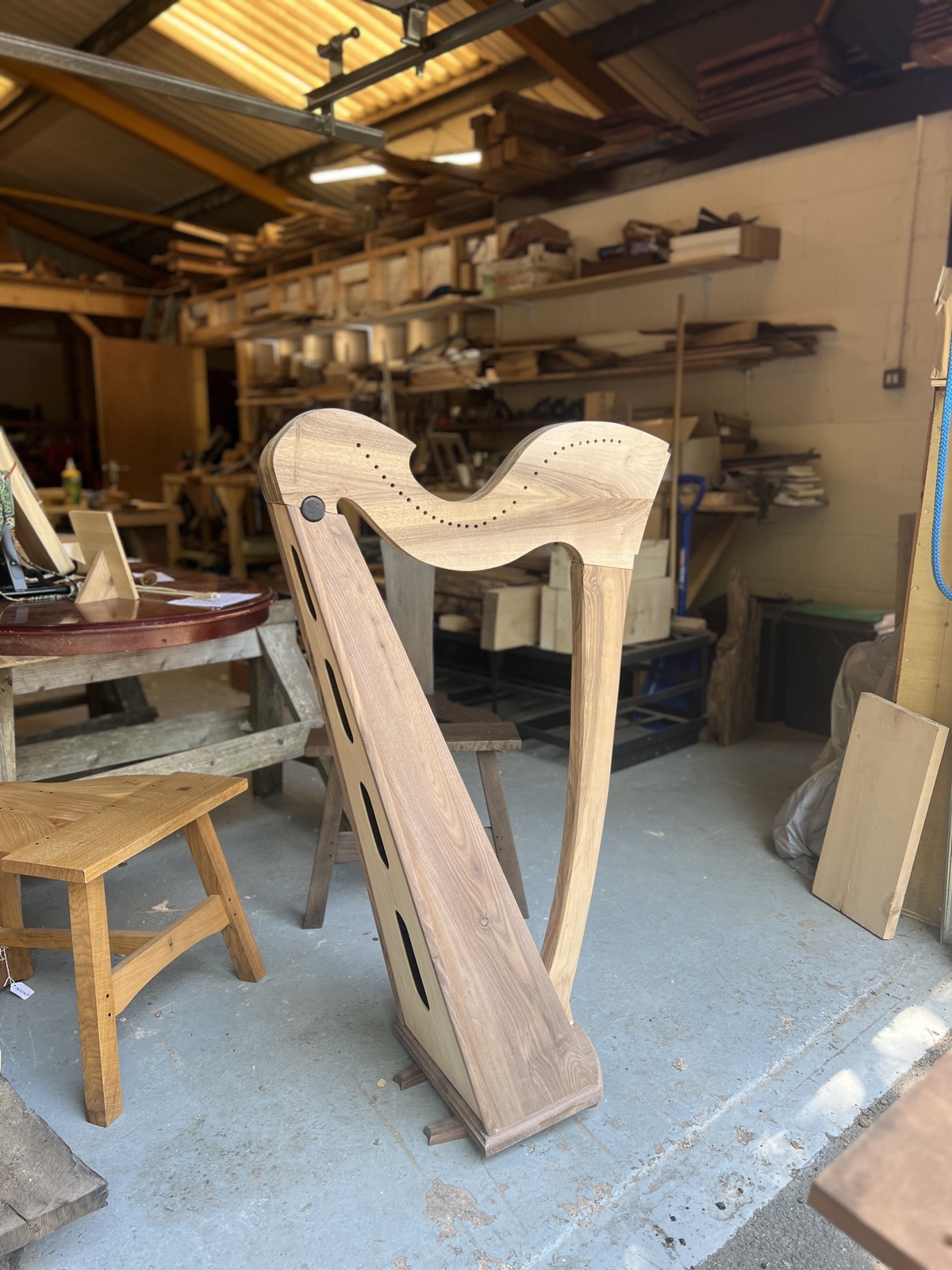 A Celtic lever harp in the white, standing in the workshop
